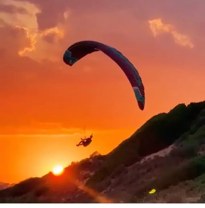 Parapendio al tramonto arancione sulla costa